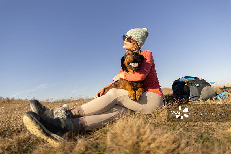 一位女士和她的狗在徒步旅行中休息。图片素材