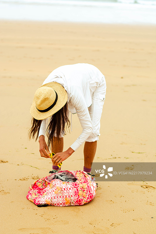 女人在阳光下翻找她的沙滩包图片素材
