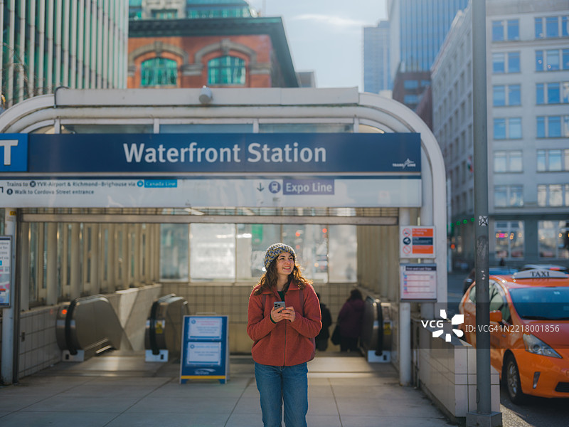 一位女性在加拿大温哥华的海滨车站使用智能手机。图片素材