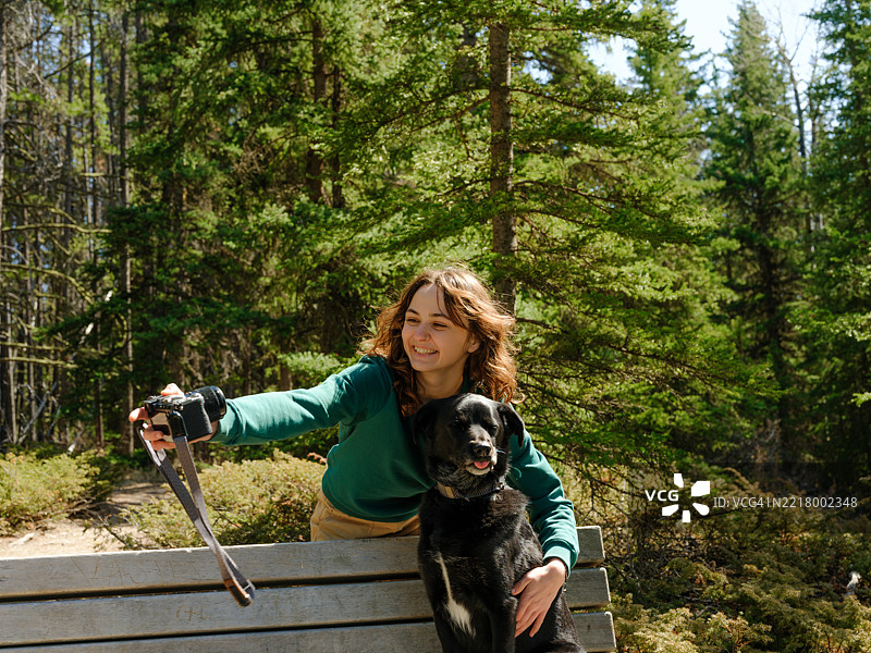 在加拿大班夫旅行时，女人与狗一起用相机自拍图片素材