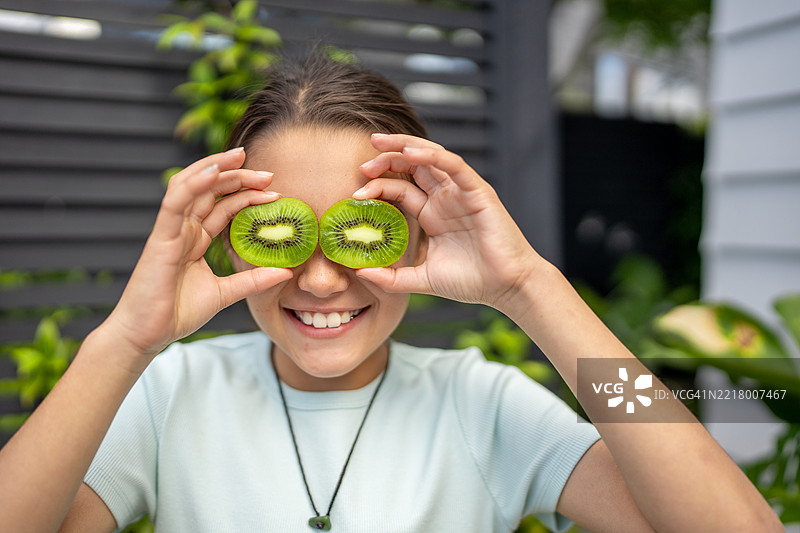 微笑的女孩用猕猴桃片遮住眼睛图片素材