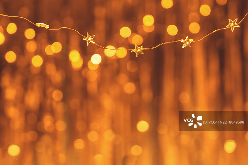 背景上模糊的金色抽象灯光与星星串灯图片素材