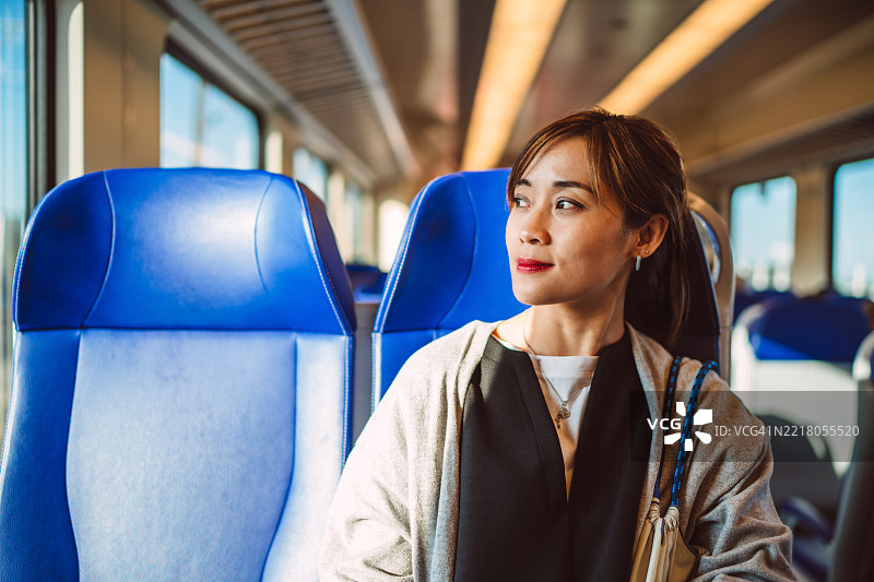 愉快的女性独自乘火车旅行，沉思地望着窗外图片素材