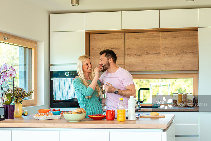 年轻的白人女性和西班牙裔男性在明亮现代的厨房里准备健康早餐图片素材