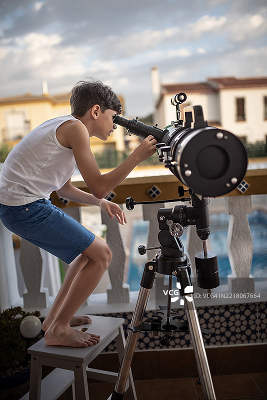 在一个夏天的日子里，一个男孩准备并调整他的望远镜，以便观察夜空。图片素材