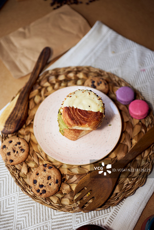 美味的开心果和白巧克力可颂，搭配饼干和马卡龙，摆放在盘子上图片素材