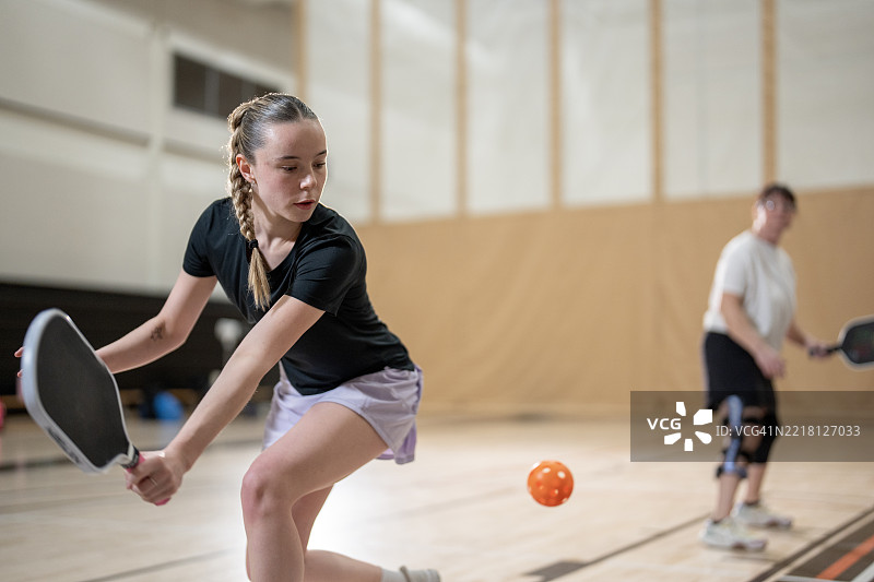活跃的球员在木质体育馆场地进行室内皮克球比赛图片素材