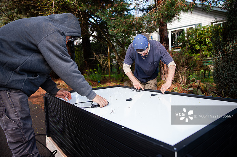太阳能面板工程师正在将太阳能面板从托盘上卸下，以便安装在屋顶上图片素材