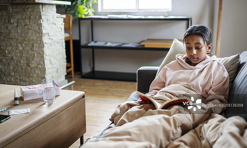 年轻女性在舒适的家居环境中放松时阅读一本书图片素材