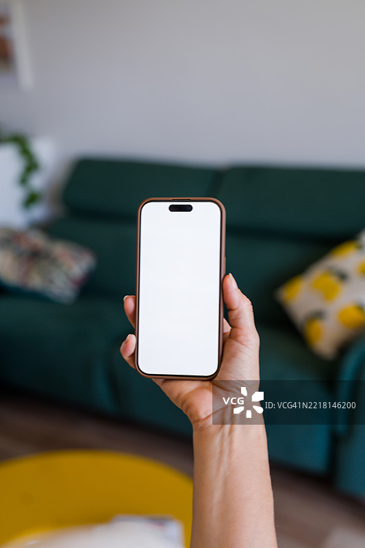 女人手持一部带有空白白色屏幕的智能手机图片素材