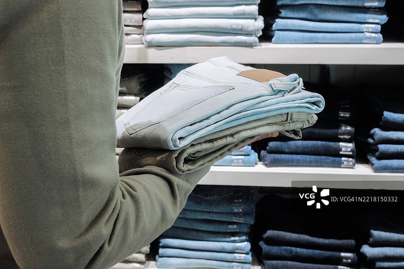 男子在商店里挑选牛仔裤图片素材