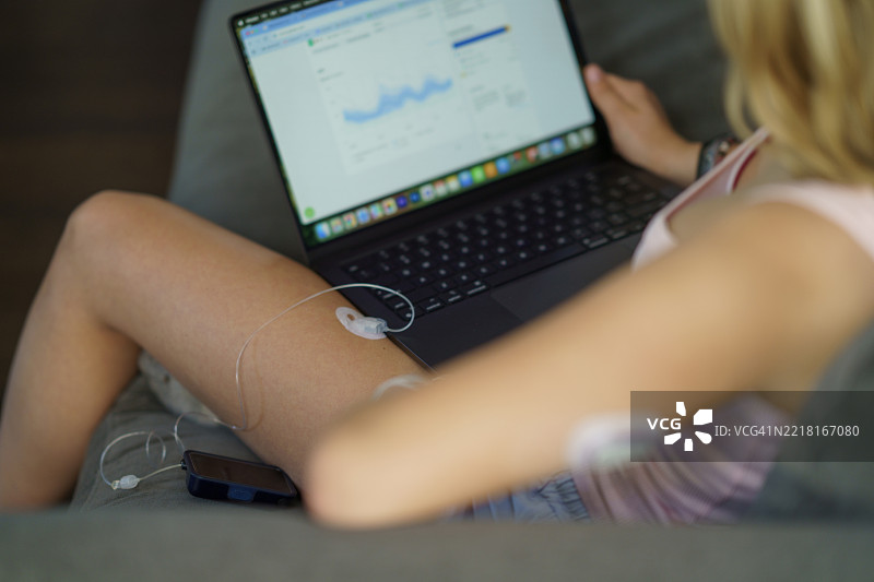 女性在沙发上使用笔记本电脑和医疗设备监测健康数据图片素材