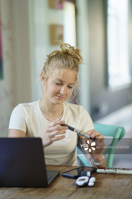 年轻女性在家中使用胰岛素笔和医疗设备管理糖尿病图片素材