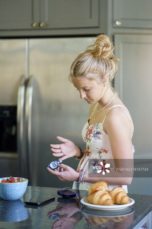 年轻女性在现代厨房环境中检查血糖水平图片素材