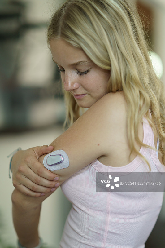 年轻女性在手臂上使用医疗设备进行健康管理图片素材