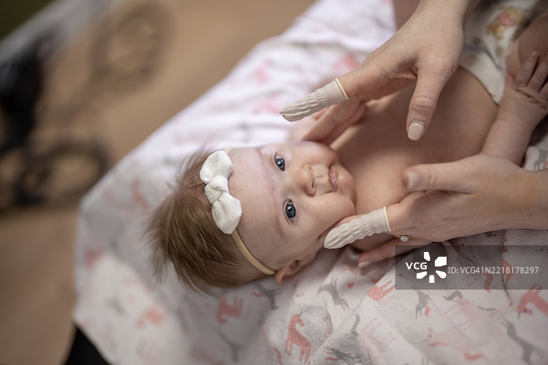 婴儿在换尿布垫上接受护理人员温柔的照顾图片素材