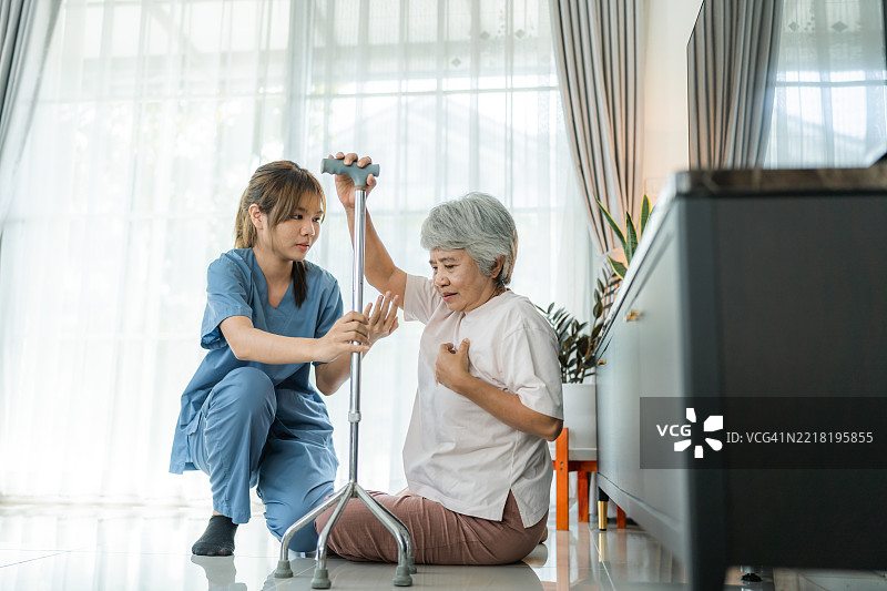 个人护理人员扶着一位老年女性，帮助她坐在沙发上图片素材