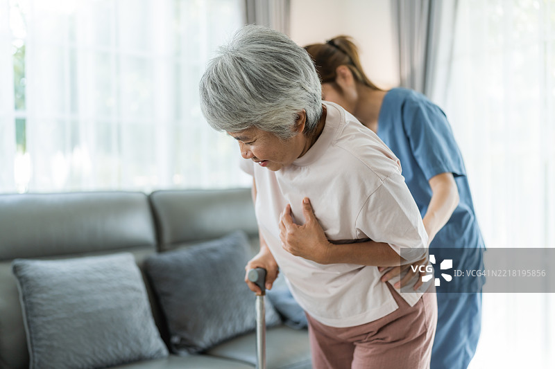 个人护理人员扶着一位老年女性，帮助她坐在沙发上图片素材