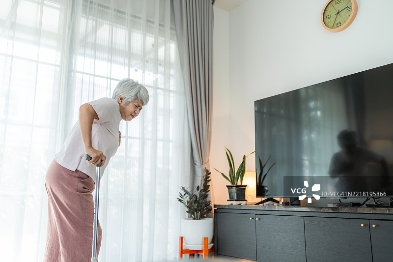 一位老年女性因手中的拐杖滑落而摔倒在地。图片素材