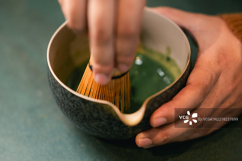 特写镜头：手心思地搅拌抹茶图片素材