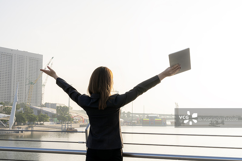 自信的年轻女商人早晨在户外查看平板电脑，灵活工作与数字连接图片素材