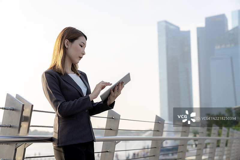自信的年轻女商人早晨在户外查看平板电脑，灵活工作与数字连接图片素材