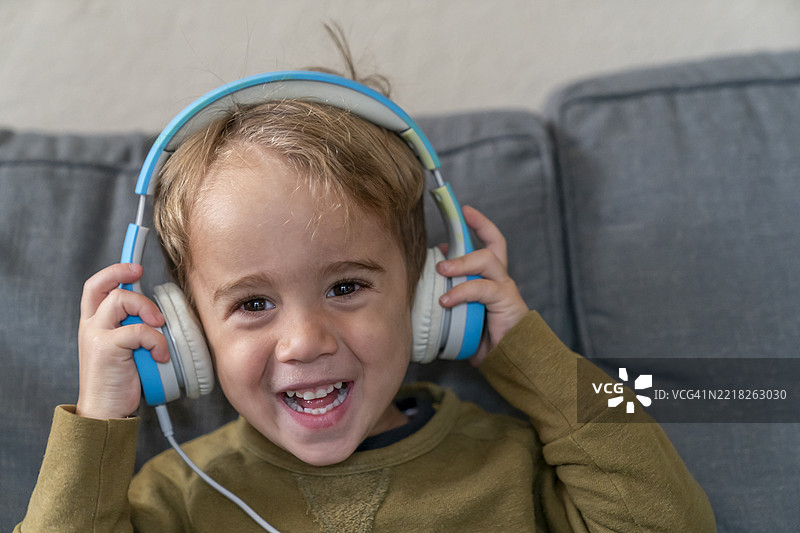 微笑的四岁男孩戴着耳机听音乐图片素材