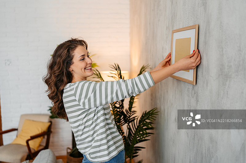 年轻女性在墙上挂画图片素材