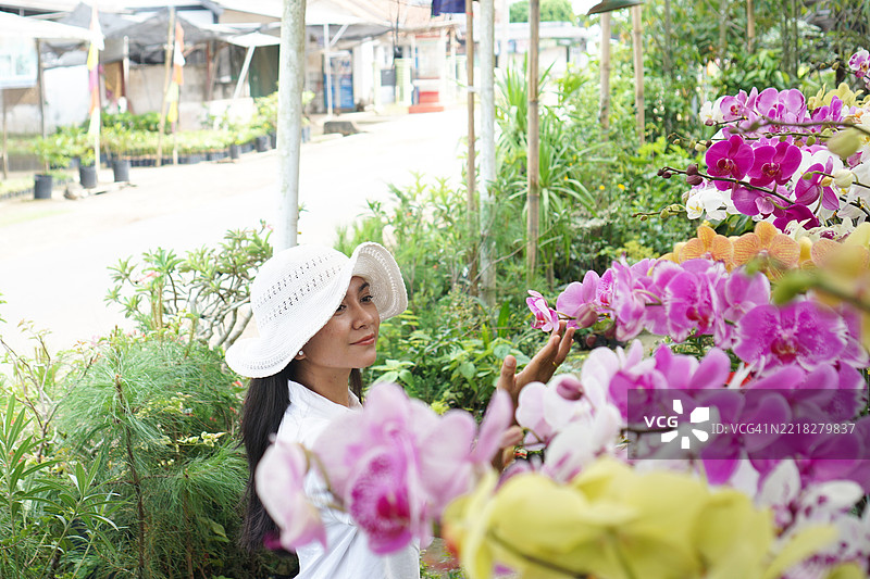 戴着帽子的女人在欣赏兰花图片素材