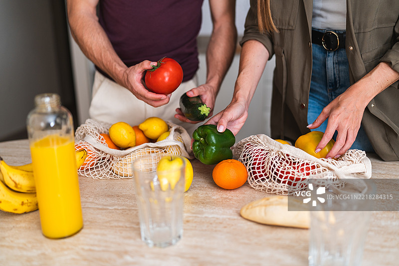 情侣在厨房桌子上整理新鲜水果和蔬菜，倡导健康生活方式图片素材