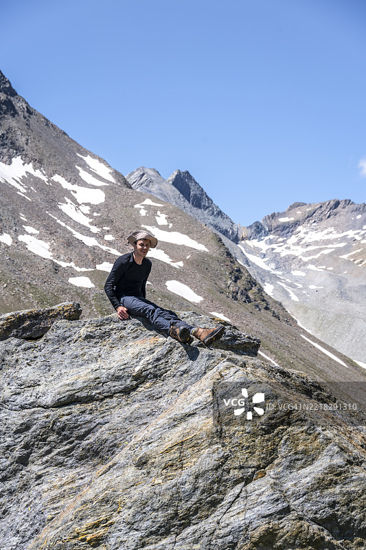 在奥地利东蒂罗尔的霍赫陶恩国家公园，一名徒步旅行者在石头上休息图片素材