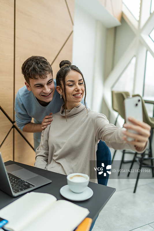 年轻情侣在咖啡馆工作时自拍图片素材