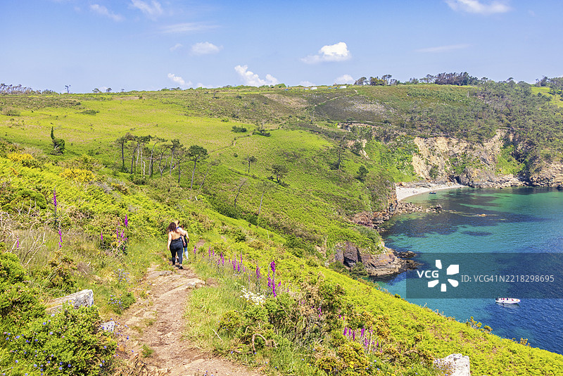 在阳光明媚的夏日，女性们在法国布列塔尼克罗宗半岛的美丽海岸区域的步道上远足，周围是岩石海岸。图片素材