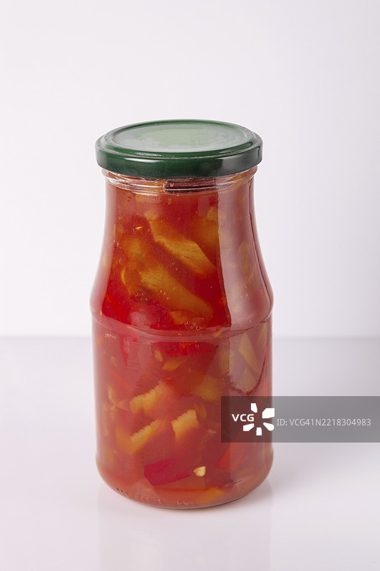 白色背景上的玻璃罐装辣椒和番茄炖菜，样品展示图片素材
