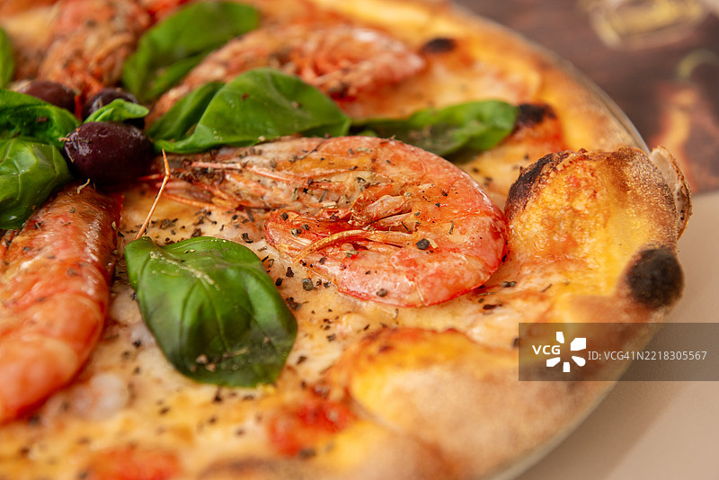 美味的披萨，上面有虾、番茄酱、马苏里拉奶酪、黑橄榄和罗勒叶图片素材