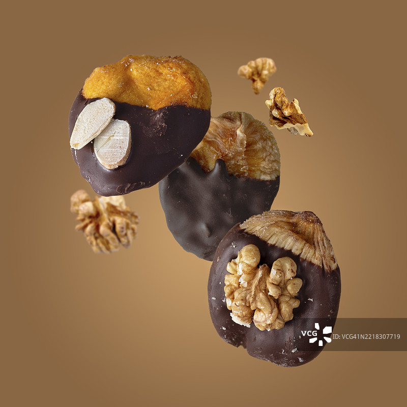 巧克力裹干果和坚果碎片，背景为米色，食物悬浮效果图片素材