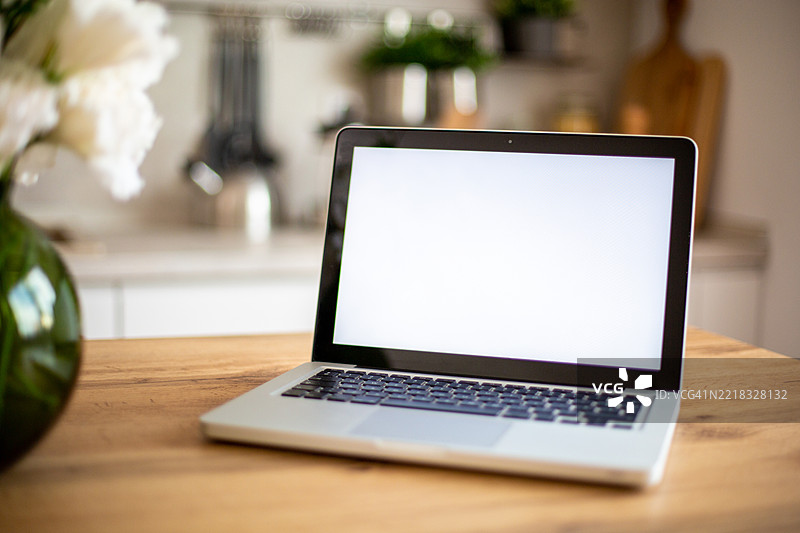 厨房木桌上放着一台黑屏的笔记本电脑图片素材