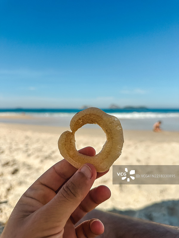 人手握着饼干的视角，位于伊帕内玛海滩图片素材