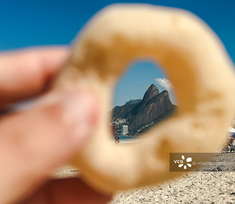 人手握着饼干的视角，位于伊帕内玛海滩图片素材