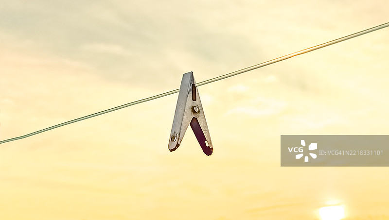 低角度视图的衣夹挂在晾衣绳上，背景是天空图片素材