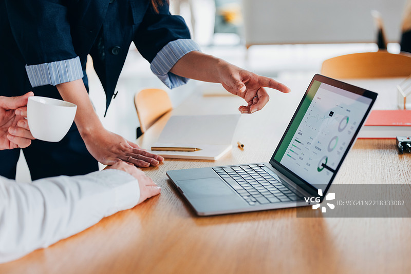 团队讨论中，笔记本电脑屏幕上显示的数据协作图片素材
