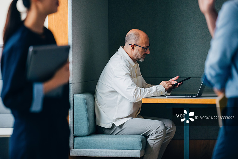 在现代办公室中专业使用智能手机和笔记本电脑图片素材