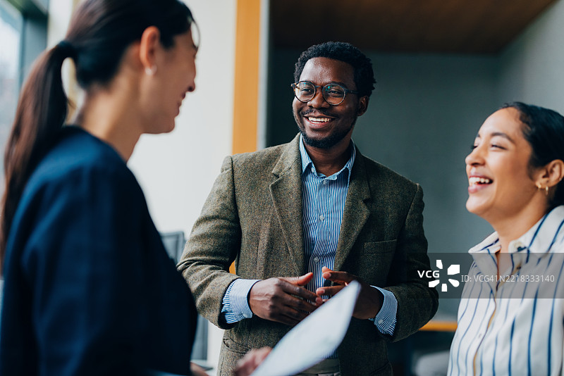 微笑的专业人士在明亮的办公室环境中进行热烈的团队讨论图片素材