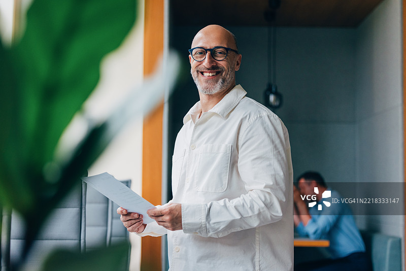 微笑的专业人士在现代办公室环境中手持文件图片素材