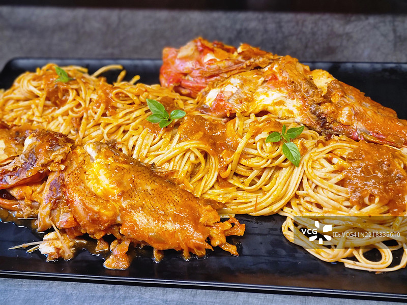 新鲜煮好的意大利面配上整条石首鱼，浸泡在美味的番茄酱中图片素材