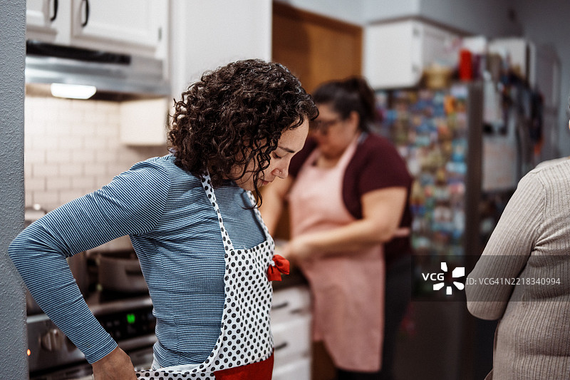 女人在和朋友一起做饭时系上围裙图片素材