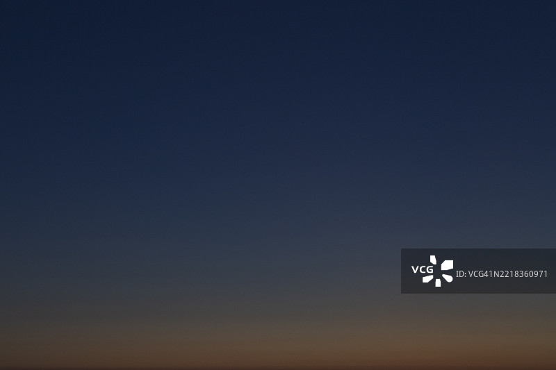 傍晚时分，橙色和深蓝色的无云天空。图片素材