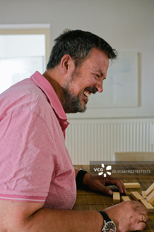 男人坐在桌子旁玩拆块游戏图片素材