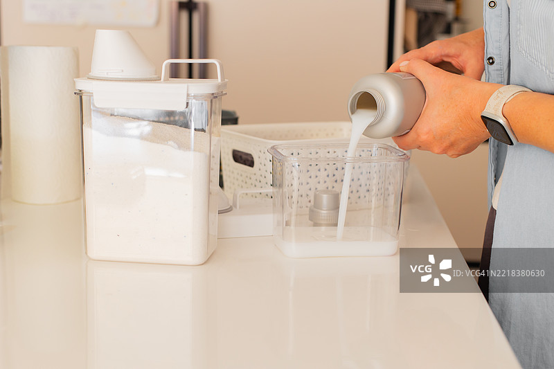 现代洗衣区中倒液体洗涤剂的人员图片素材