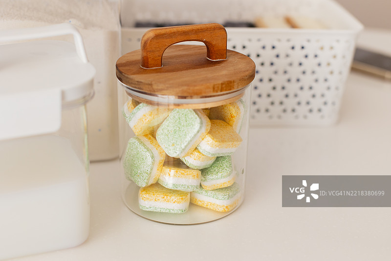 带有黄色和绿色标签的透明容器，适用于整洁厨房中的洗碗机图片素材